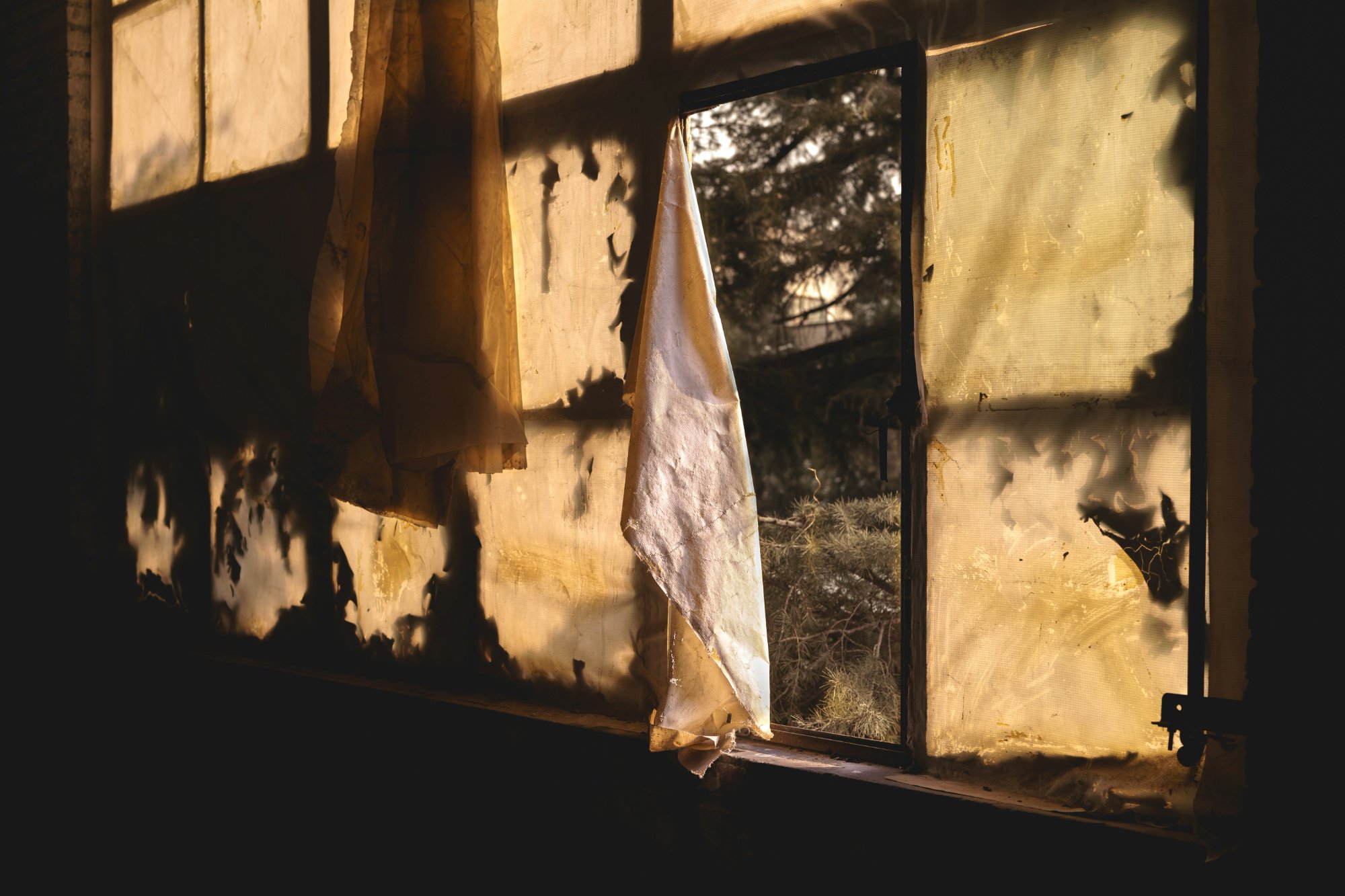Abandoned window with torn curtain and dramatic light — the haunted space of nightmares
